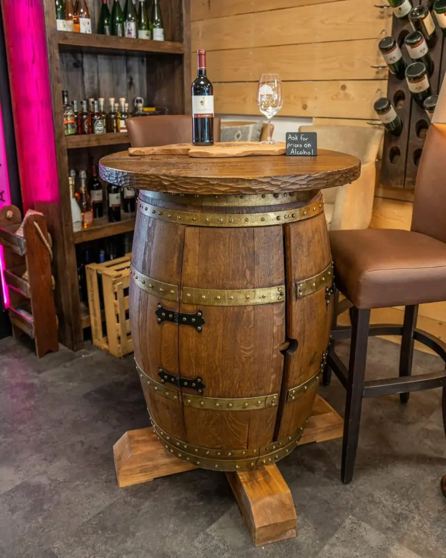 Stehtisch aus einem Barrique-Weinfass vor einem Weinregal