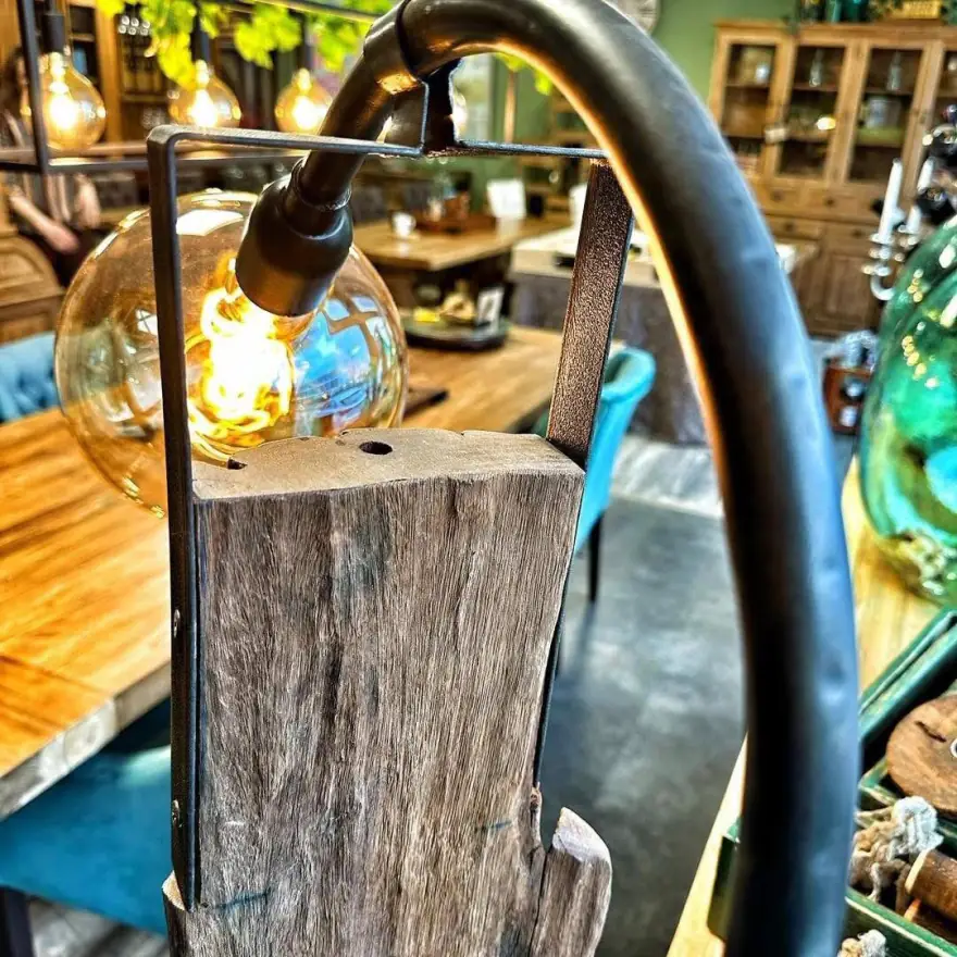 Tischlampe aus einem Baumstamm mit geschwungenem Metallbügel