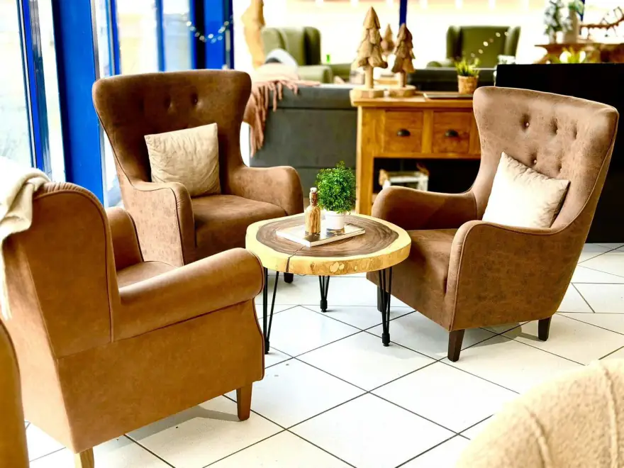 Zwei braune Ohrensessel mit einem Beistelltisch aus einer Baumscheibe im Showroom